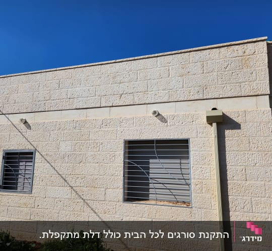 סורגים ישרים ממתכת המותקנים על חלונות בבית עם חיפוי אבן